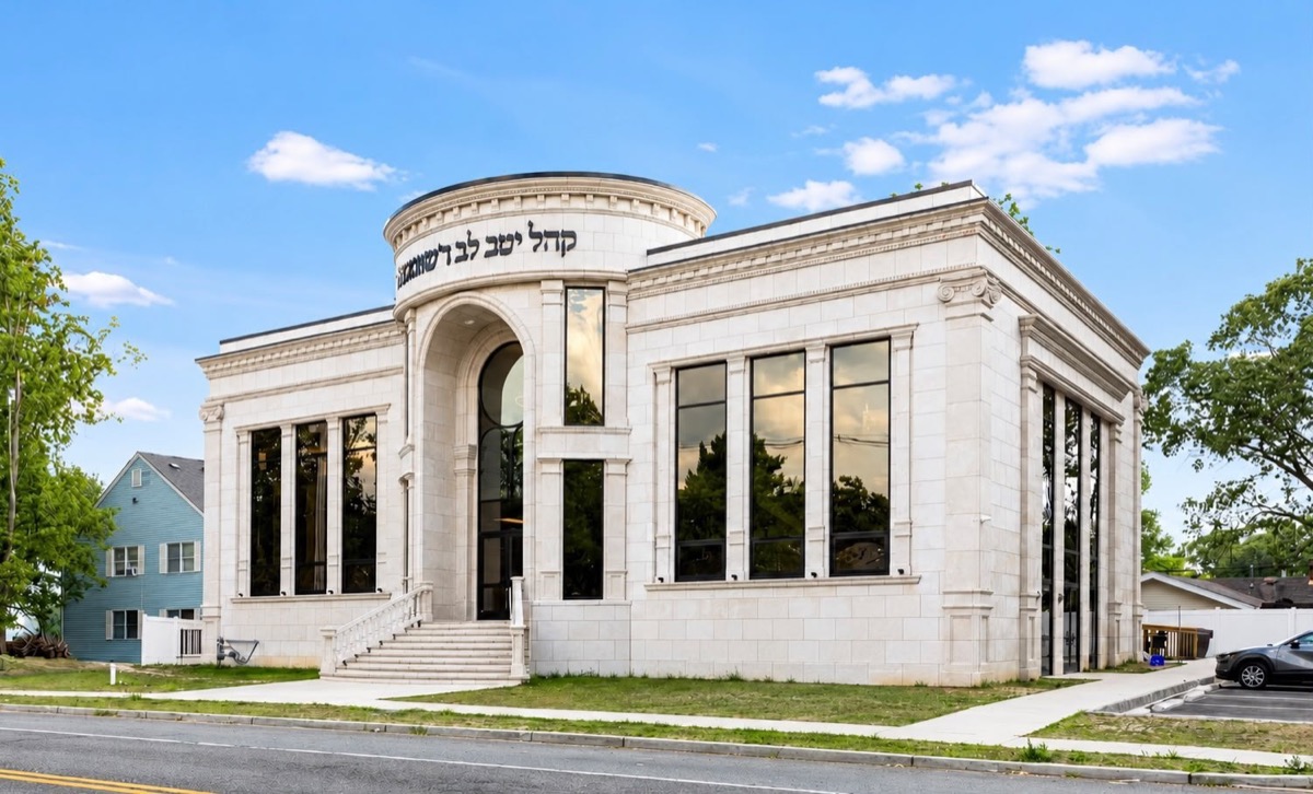 Stone shul with an arched entry and tall black windows